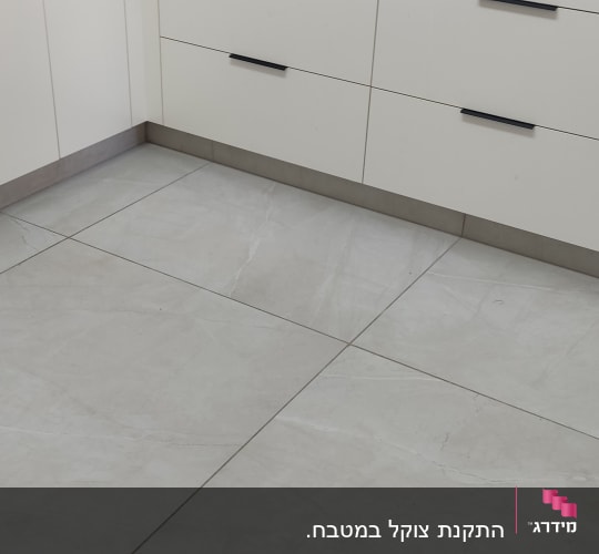 אריחי רצפה חדשים ליד ארונות מטבח לבנים